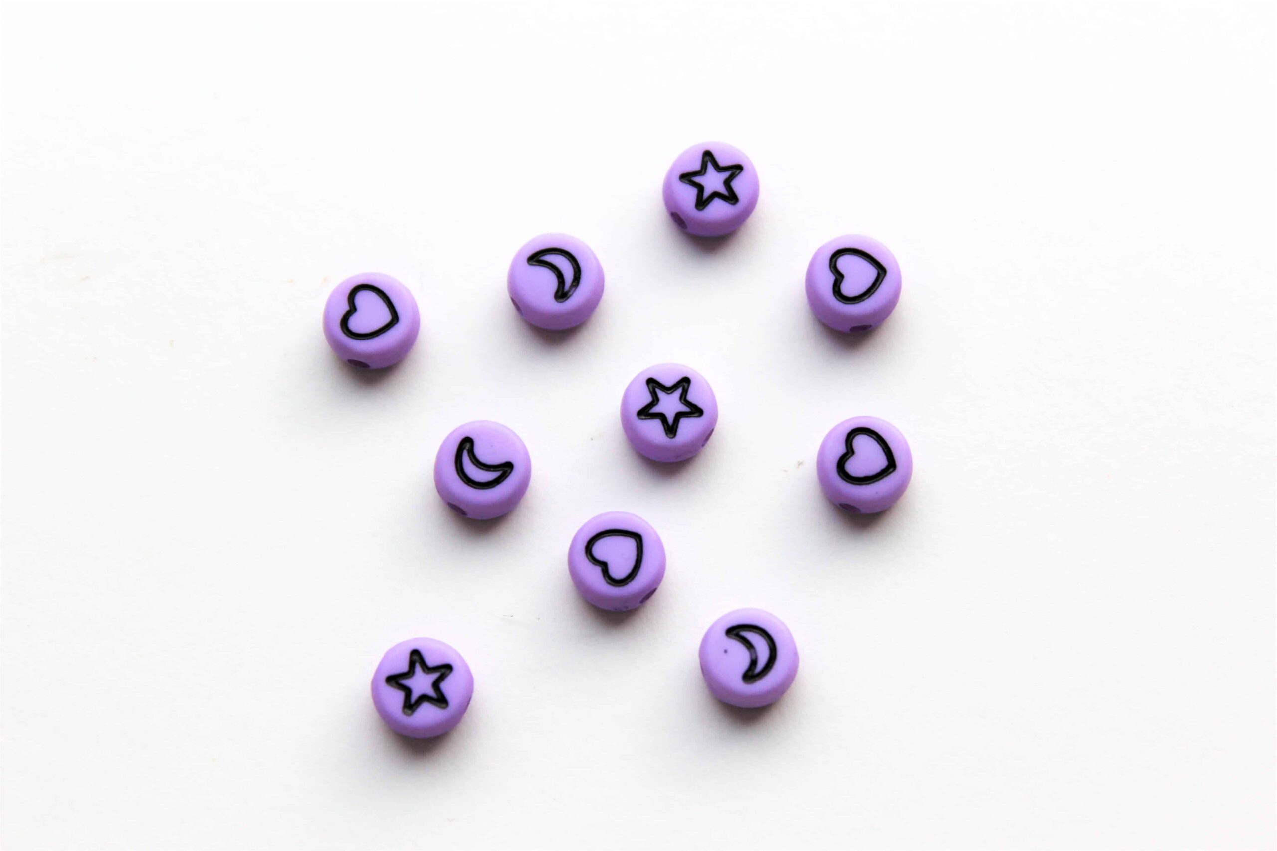 Akrylperler, runde, lys lilla, med ulike motiver.