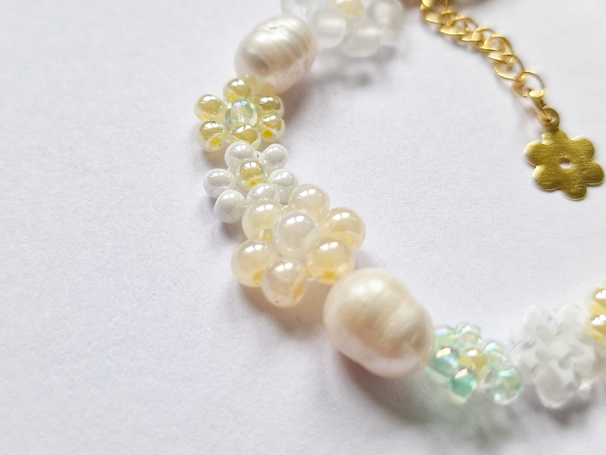 Håndlaget perlearmbånd med blomster i gult, grønt og hvitt. Seed beads, ferskvannsperler og gullforgylt lås.