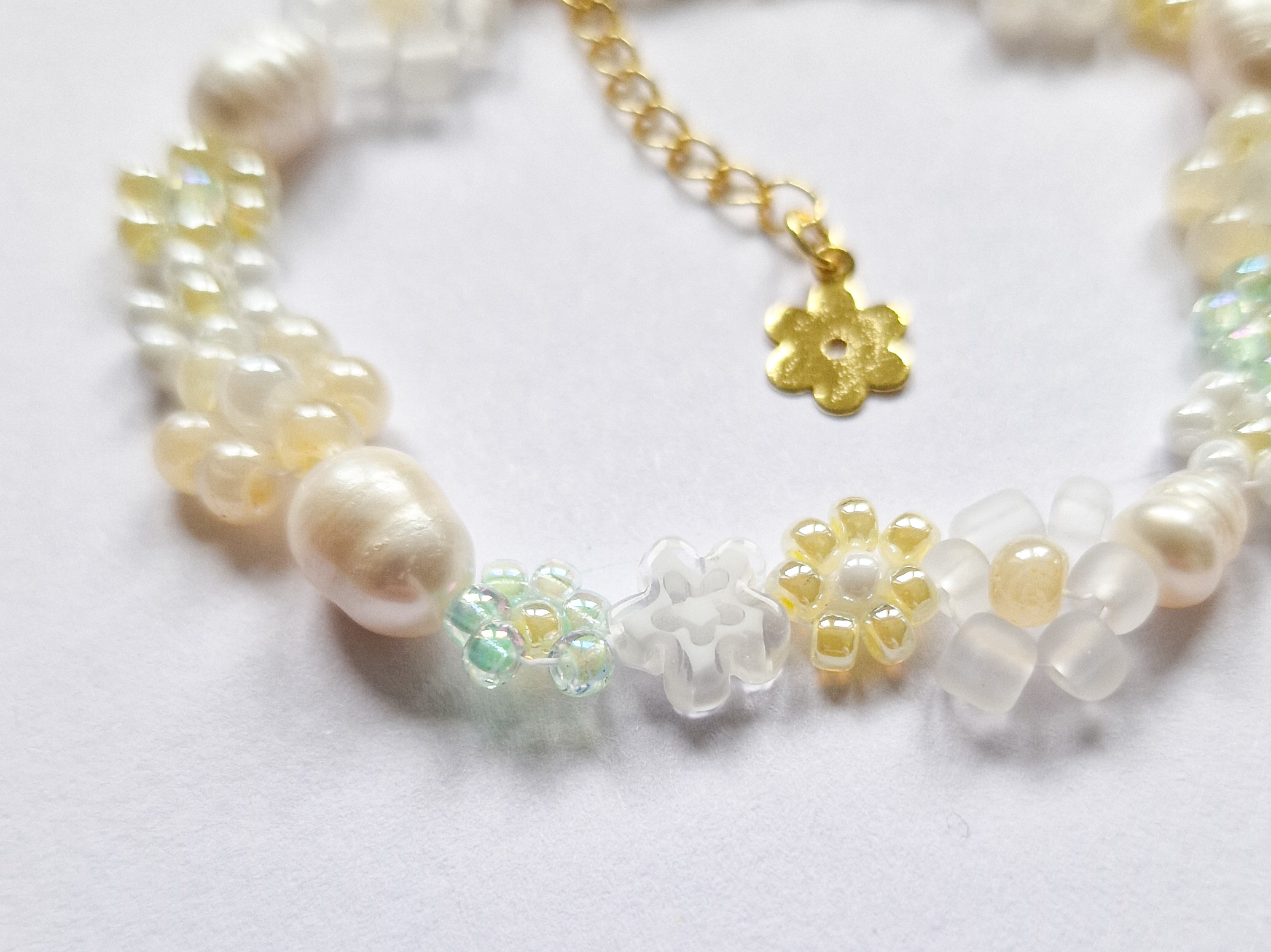 Håndlaget perlearmbånd med blomster i gult, grønt og hvitt. Seed beads, ferskvannsperler og gullforgylt lås.