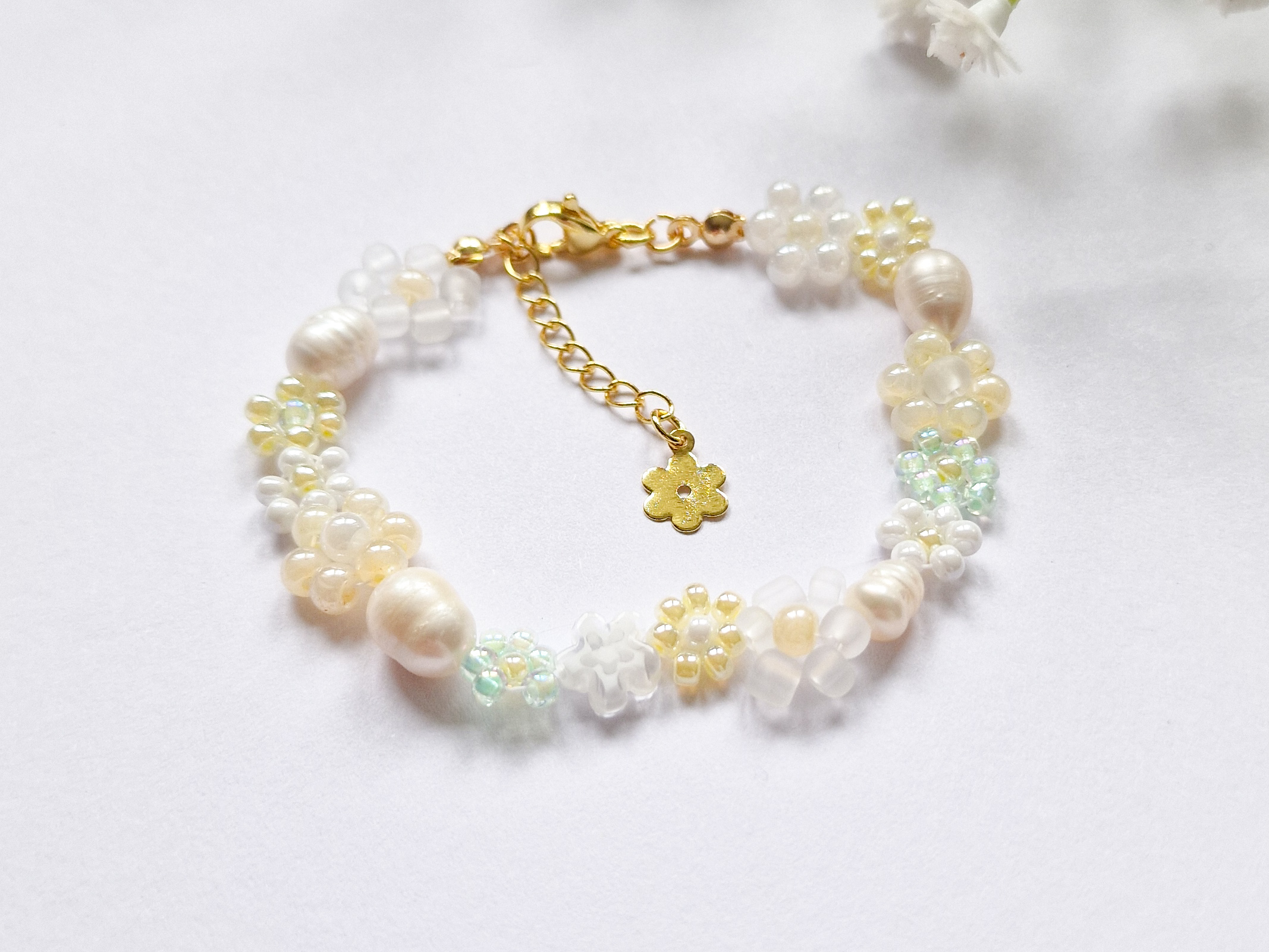 Håndlaget perlearmbånd med blomster i gult, grønt og hvitt. Seed beads, ferskvannsperler og gullforgylt lås.